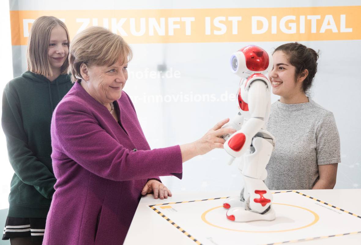 Bundeskanzlerin Angela Merkel macht beim Girls Day am Stand des Fraunhofer-Instituts Bekanntschaft mit dem Roboter Nao.