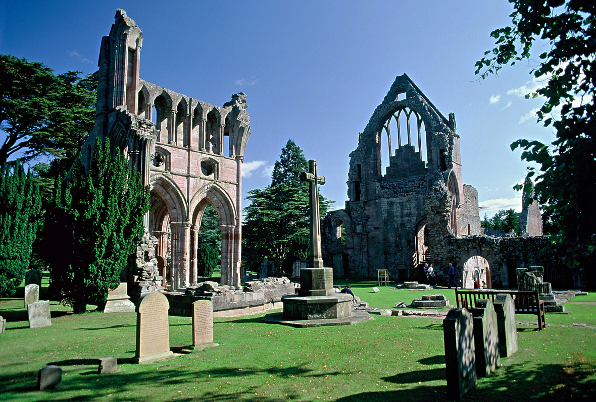 Die Ruinen von Dryburgh Abbey ragen in Dryburgh in den blauen Himmel. Das Kloster wurde 1150 gegründet. Es brannte zwei Mal nieder und wurde wieder aufgebaut, bis es 1544 endgültig zerstört wurde. Dryburgh liegt in der Region Scottish Borders, einer Hügellandschaft in Schottland, und gehört zu den Southern Uplands.