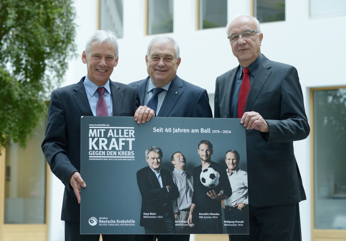 Der Vorstandsvorsitzende Hans-Peter Krämer (M), der Präsident der Deutschen Krebshilfe, Fritz Pleitgen und der Hauptgeschäftsführer, Gerd Nettekoven, präsentieren ein Plakat ihrer laufenden Kampagne. Das Plakat zeigt vier Sportler und den Slogan "Mit aller Kraft gegen den Krebs".