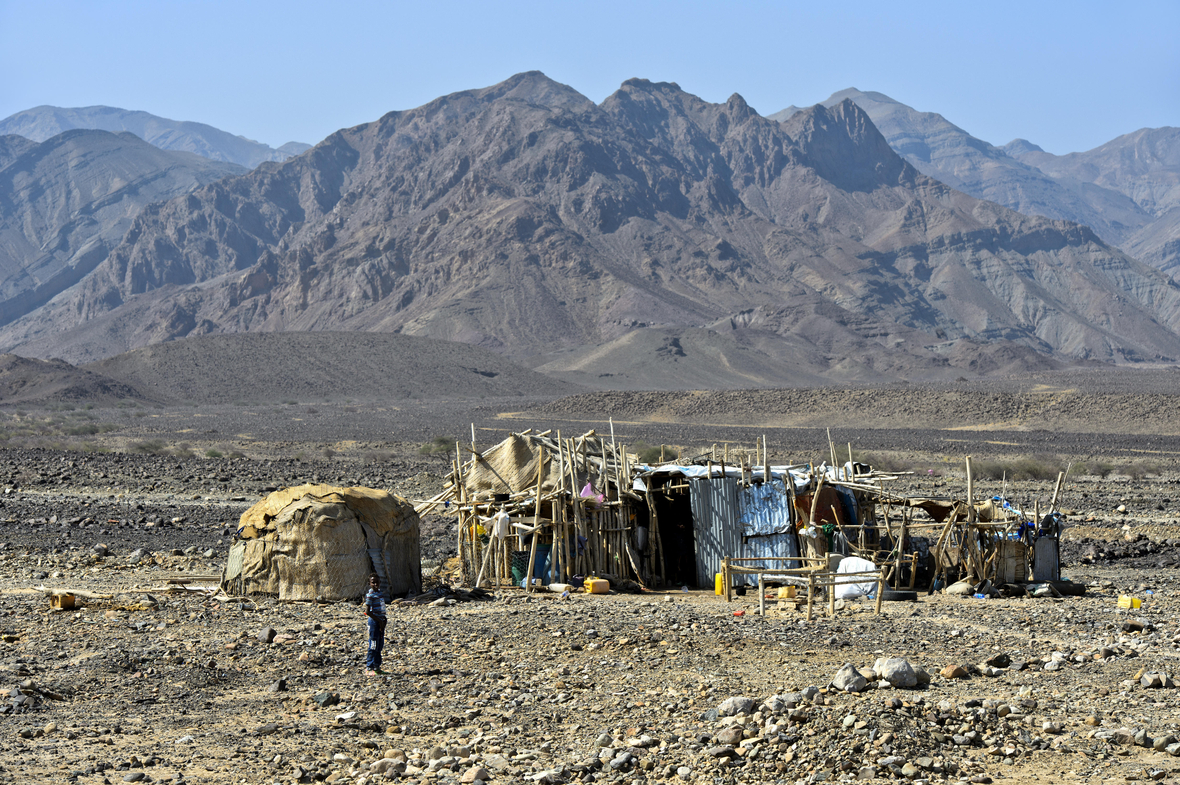 Traditionelle Unterkunft der Afar Nomaden in Äthiopien. Man sieht einfache Hütten in einer steinigen Landschaft. 