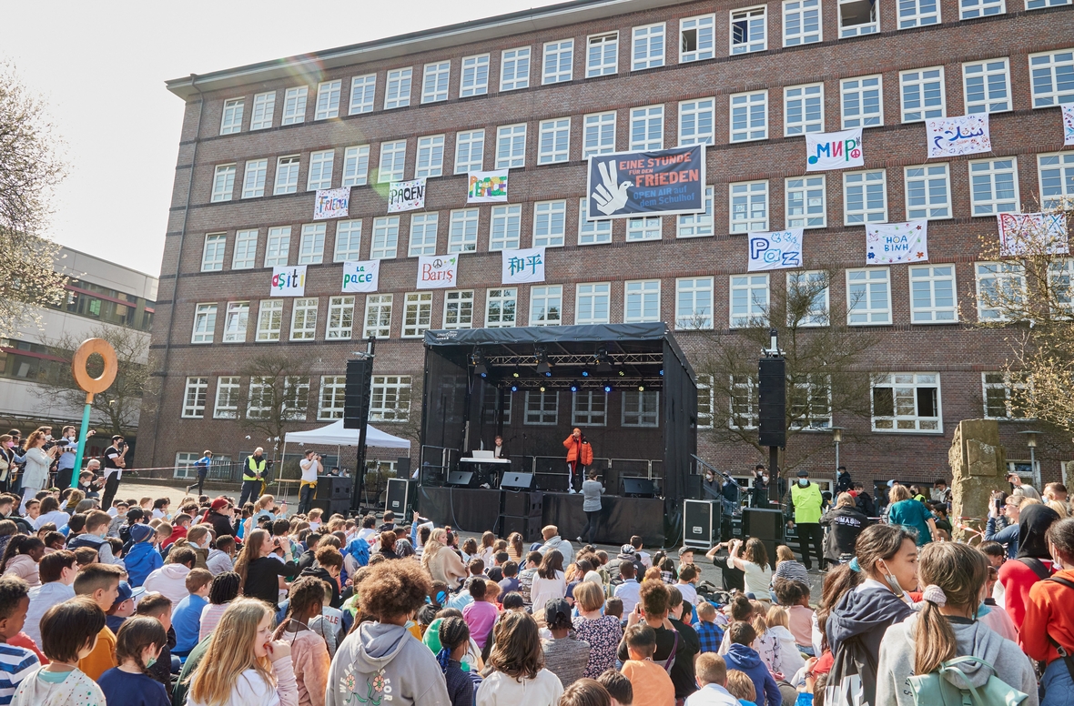 Bühnenshow "Eine Stunde für den Frieden" an einer Schule in Hamburg. An den Fenstern hängen Friedensbotschaften in verschiedenen Sprachen.