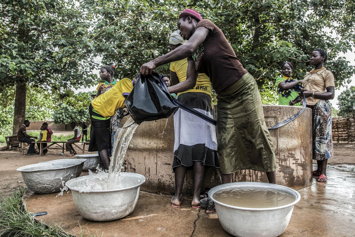 Durch internationale Unterstützung konnte die Versorgung mit Trinkwasser in SinendÄ, Benin, Afrika, sichergestellt werden. Jetzt können Mädchen statt Wasser zu schleppen zur Schule gehen. Auch die Krankheiten durch verseuchtes Wasser haben abgenommen. Hier wird ein Brunnen gezeigt, aus dem sich mehrere Frauen mit Wasser versorgen. 
