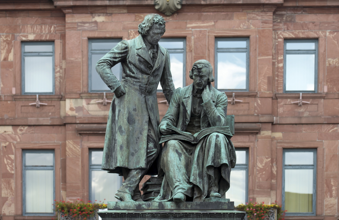 Das Brüder-Grimm-Denkmal von 1896 mit Wilhelm Grimm sitzend und Jacob Grimm stehend auf dem Marktplatz vor dem Rathaus in Hanau. Die hessische Stadt ist die letzte Station der Deutschen Märchenstraße.