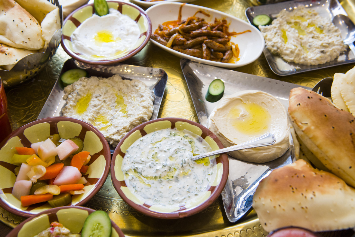 Verschiedene Schüsseln mit unterschiedlichen Vorspeisen wie Fladenbrot, Hummus oder Gemüse.