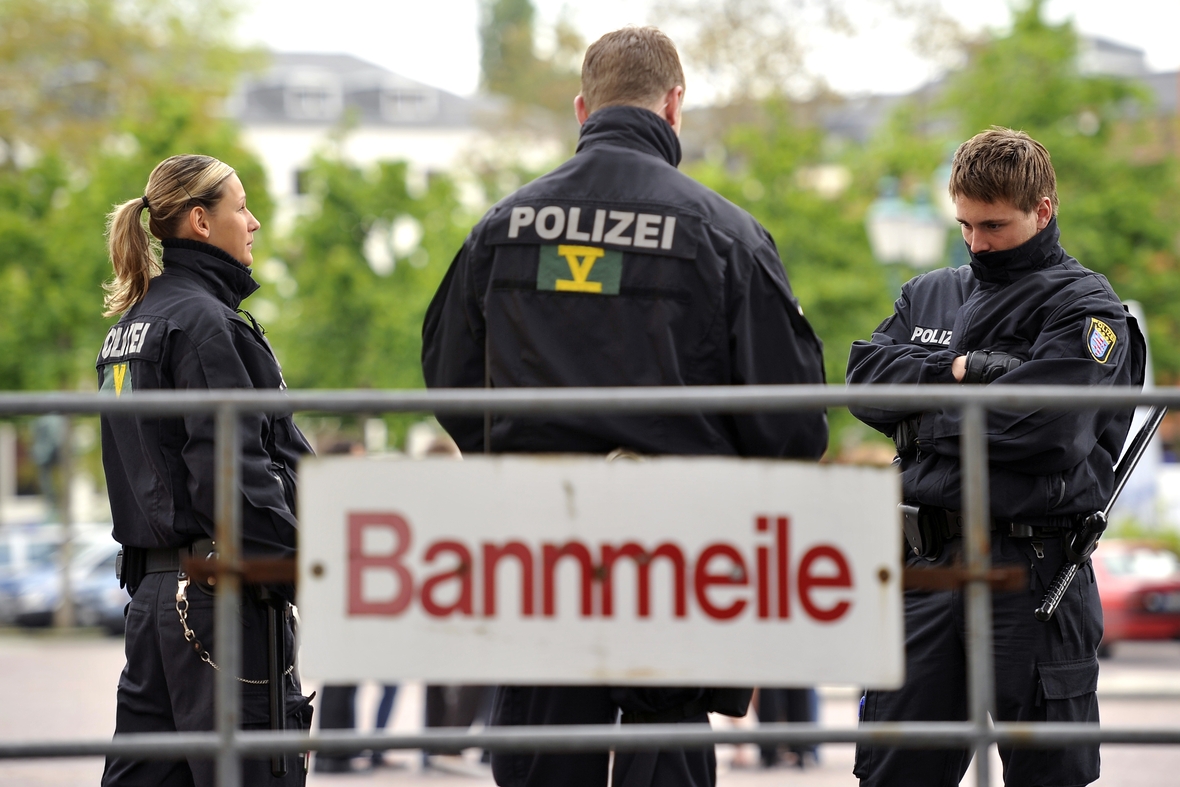 Polizist/innen sichern eine Bannmeile. Auf einem Sperrgitter ist das Wort "Bannmeile" zu lesen.