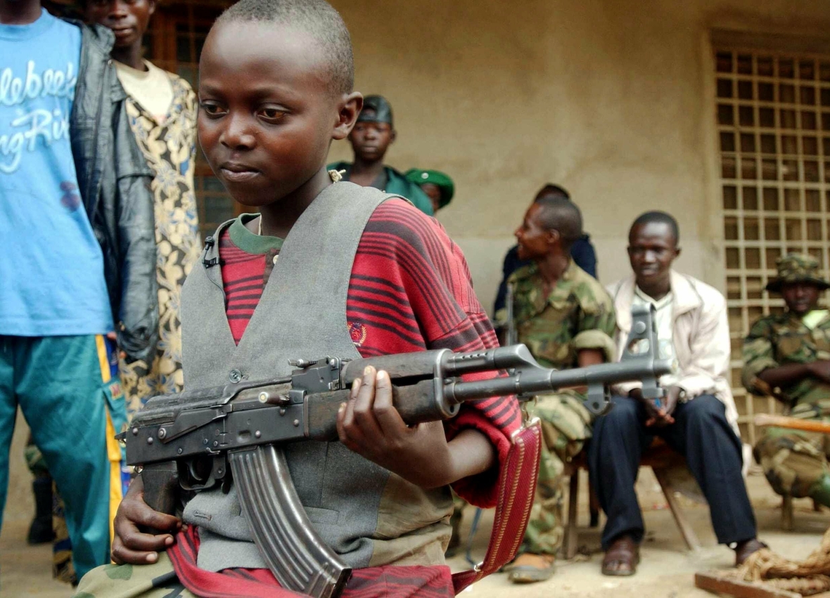 Ein zwölfjähriger Kindersoldat im Kongo 2003. Mit seiner Waffe in der Hand beobachtet er die Menschen auf der Straße.