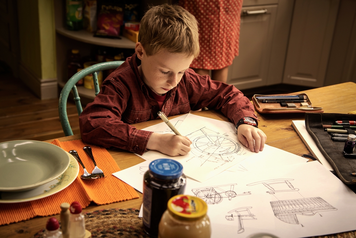 Szenenbild: Der Junge T.S. Spive, ein hochbegabter Erfinder und Zeichner, arbeite am Schreibtisch