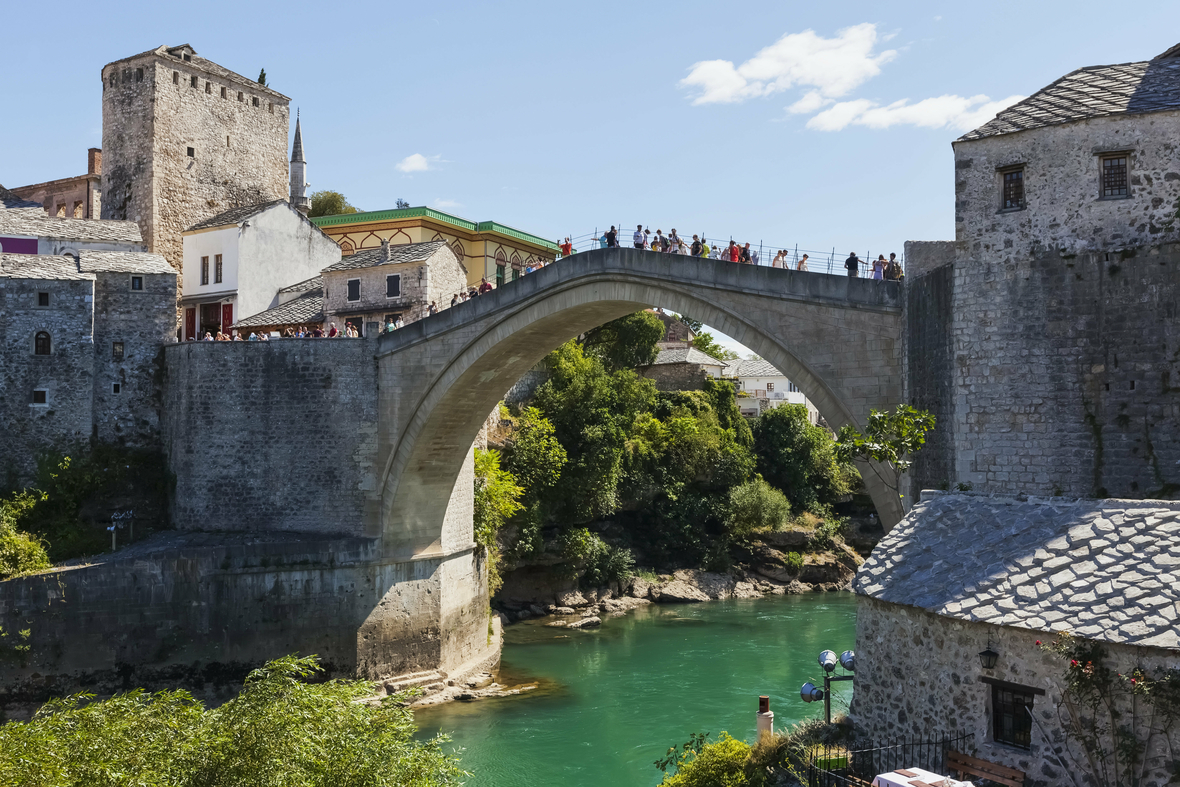 Die Aufnahme zeigt die bekannte Mostar-Brücke über den Fluss Neretva in der Stadt Mostar in Bosnien und Herzegowina. Auf der Steinbrücke spazieren Menschen.
