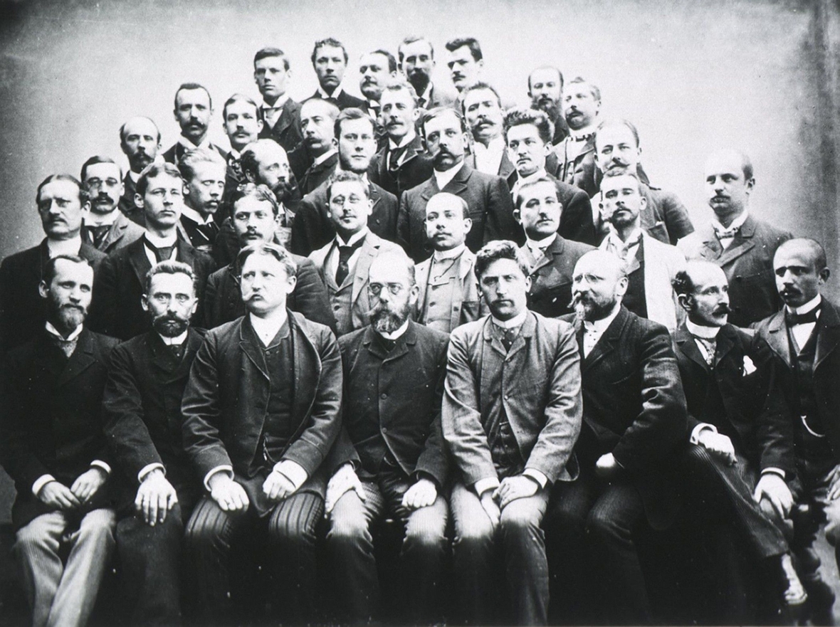 Robert Koch sitzt 1891 inmitten von jungen Forschern, die bei ihm Bakteriologie (Wissenschaft über Bakterien) studiert haben. Nur Männer sind auf dem Bild zu sehen - erst neun Jahre später konnte die erste Frau an einer deutschen Universität ihr Studium beginnen.