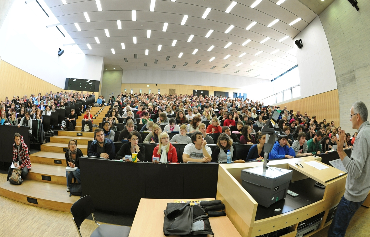 Studierende in der Universität Halle sitzen im Hörsaal und lauschen einem Professor.