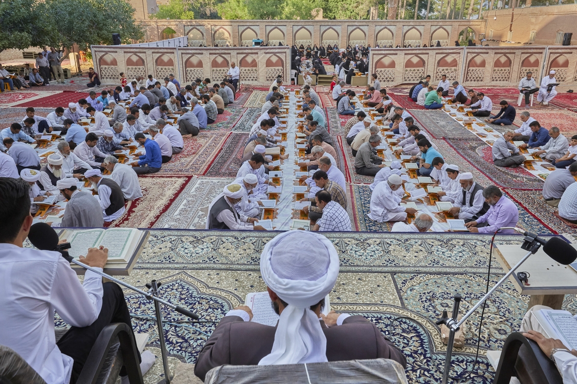 Abendliches Ramadangebet von Sunniten in einer Moschee im Iran. Beter knien sich gegenüber mit gebeugten Rücken.