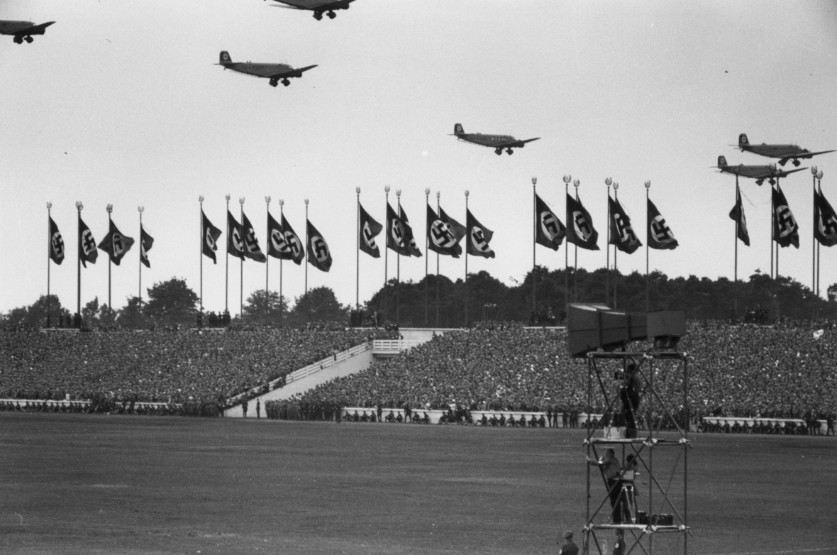 Reichsparteitag der NSDAP 1936 in Nürnberg. Man sieht ein mit Menschen gefülltes Stadion und Fahnen der NSDAP.