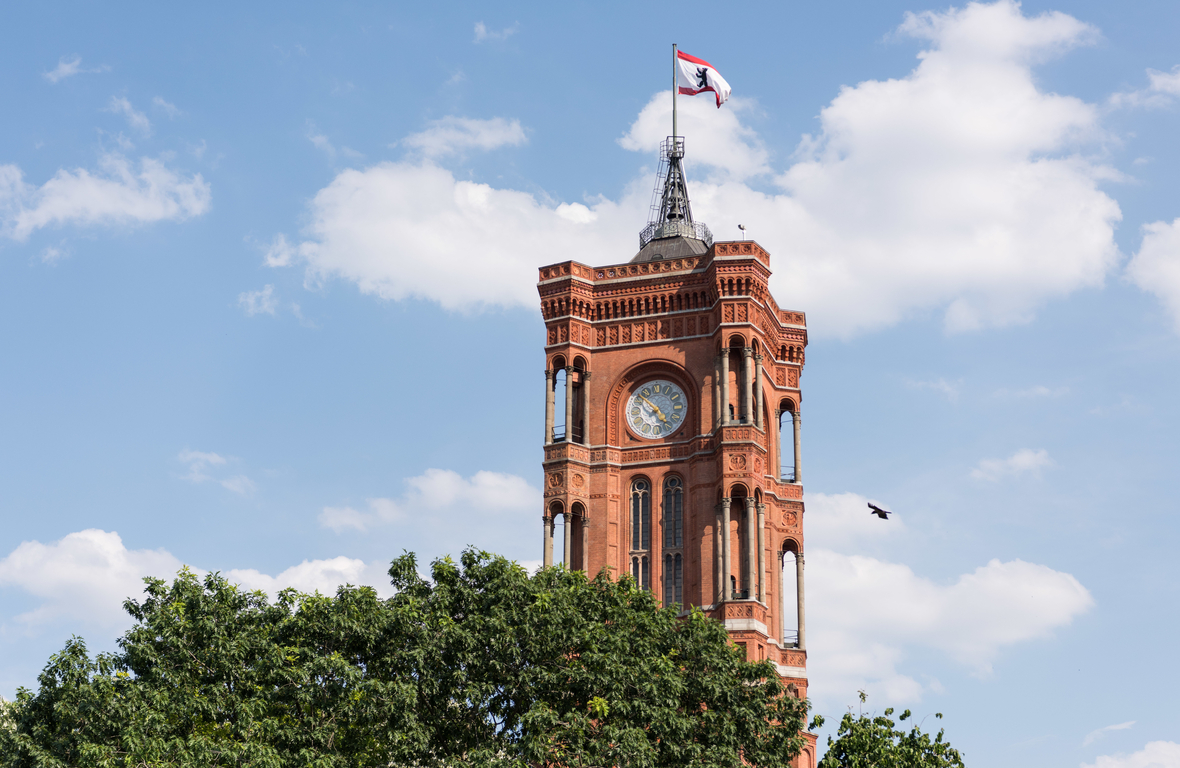 Der Turm des Berliner Rathauses, auch  Rotes Rathaus genannt, vor blauem Himmel mit der Berliner Fahne.