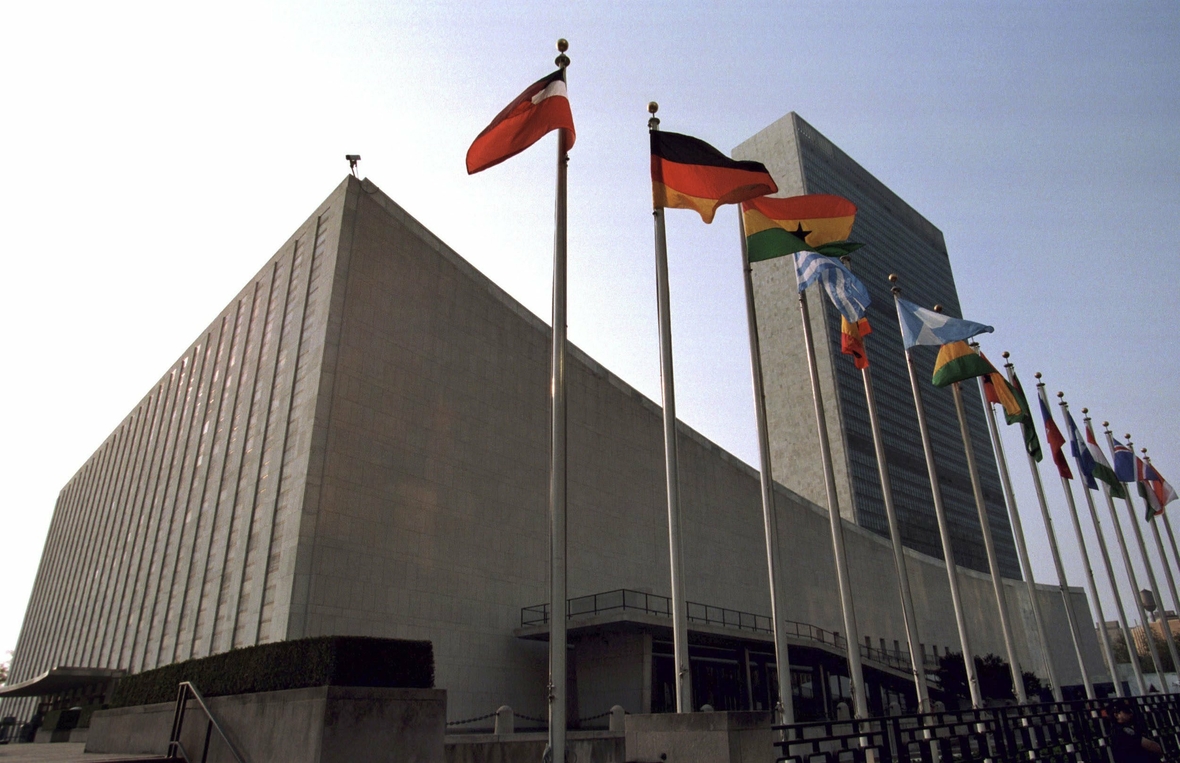 Das Gebäude der Vereinten Nationen (UNO) am East River in New York City. Im Vordergrund wehen die Flaggen der UNO-Mitgliedsstaaten.