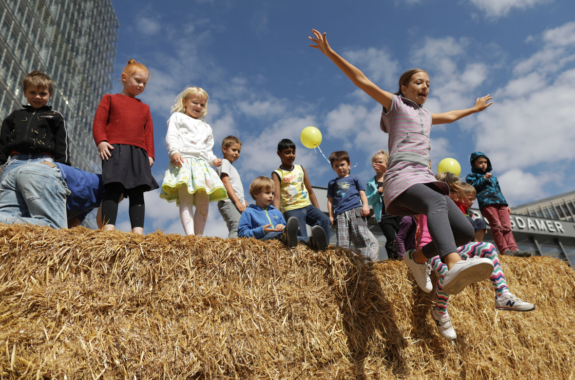 Kinder springen beim 27. Weltkindertagsfest am 18.09.2016 auf dem Potsdamer Platz in Berlin von aufgestapelten Heuballen in ein Strohbett. Der Weltkindertag steht unter dem Motto "Kindern ein Zuhause geben".