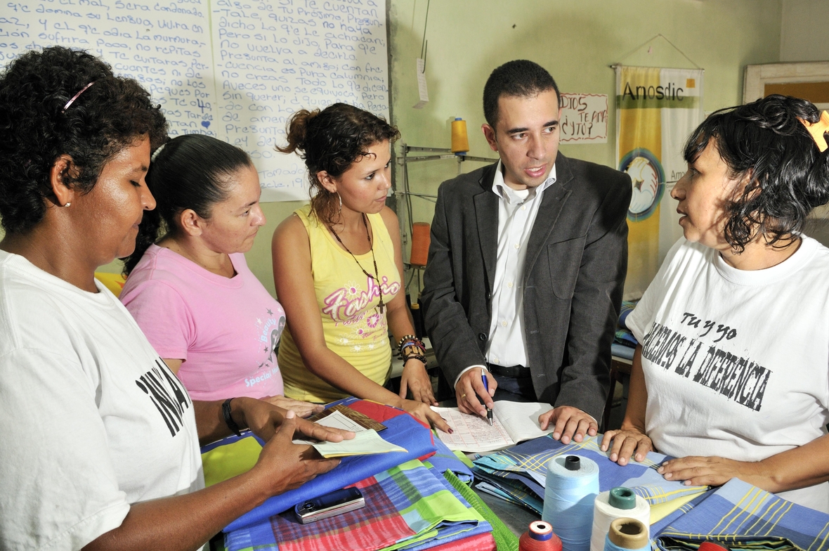 Kolumbien, Südamerika: Ein Entwicklungshelfer berät Schneiderinnen bei der Buchhaltung ihrer Geschäfte.
