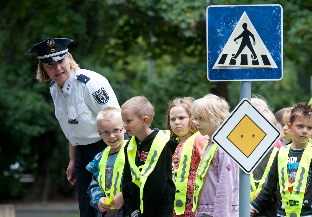 Kinder lernen mit einer Polizistin das richtige Verhalten im Verkehr.