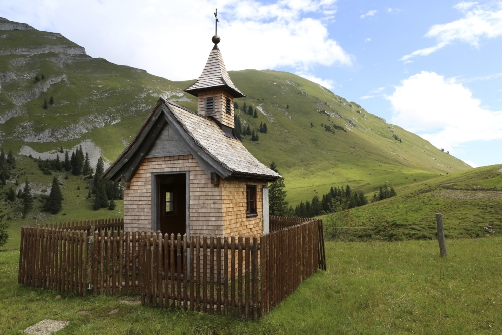 Eine Kapelle im Bregenzerwald in Österreich. Die kleine Kapelle steht auf einer Alm und ist von einem kleinen Zaun umgrenzt. 