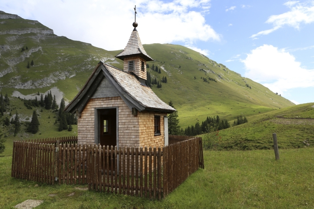 Eine Kapelle im Bregenzerwald in Österreich. Die kleine Kapelle steht auf einer Alm und ist von einem kleinen Zaun umgrenzt.