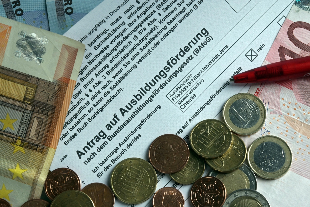Ein Formular trägt die Aufschrift "Antrag auf Ausbildungsförderung". Um das Formular herum liegen Geldscheine und Münzen.