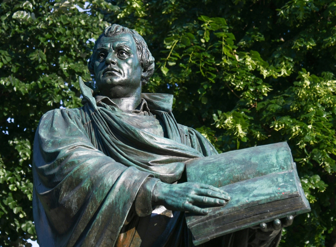 Das Martin Luther-Denkmal in Berlin zeigt den Reformator in einer Mönchskutte mit einer aufgeschlagenen Bibel in der Hand.