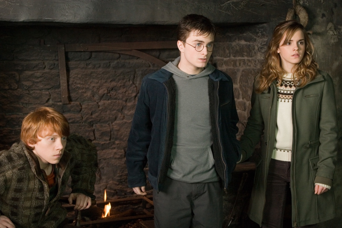 Szenenbild, von links nach rechts: Ronald sitzt in einem Stuhl, Harry Potter und Hermine stehen daneben. Sie schauen überrascht.