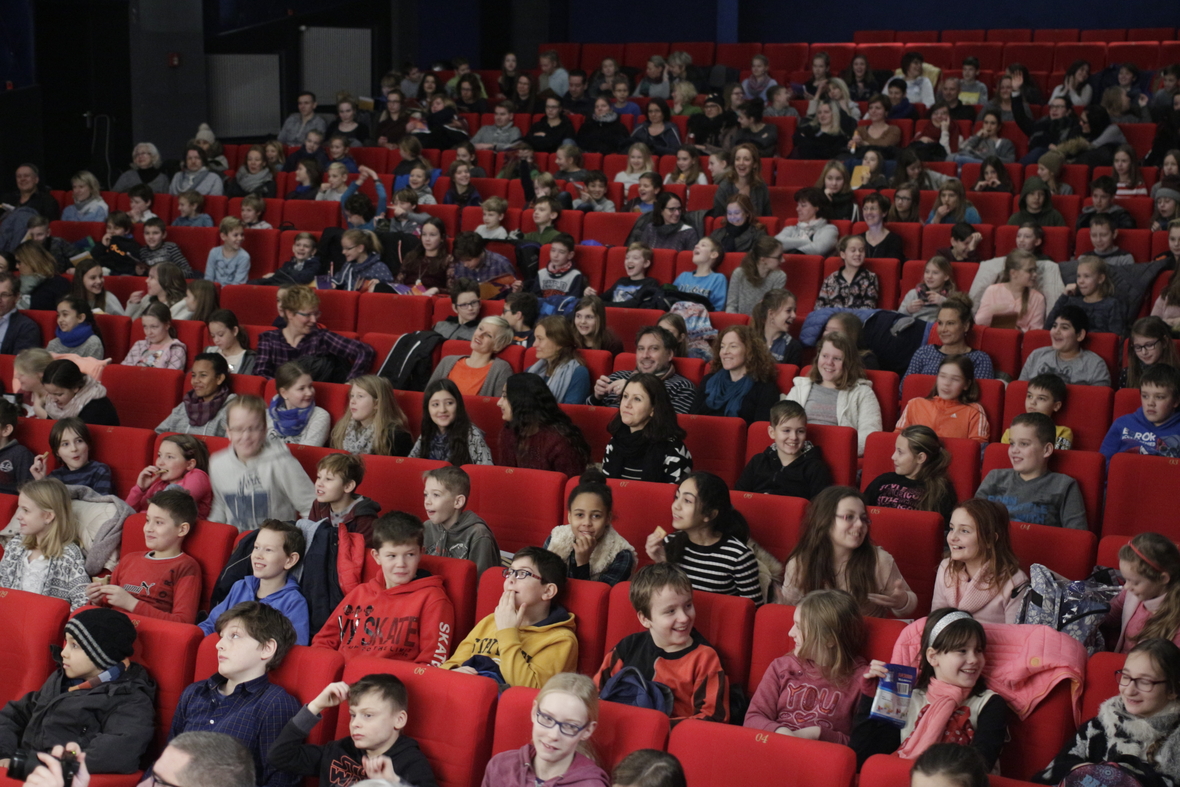 Gespannte Kinder bei einer Filmpremiere in einem großen Kinosaal