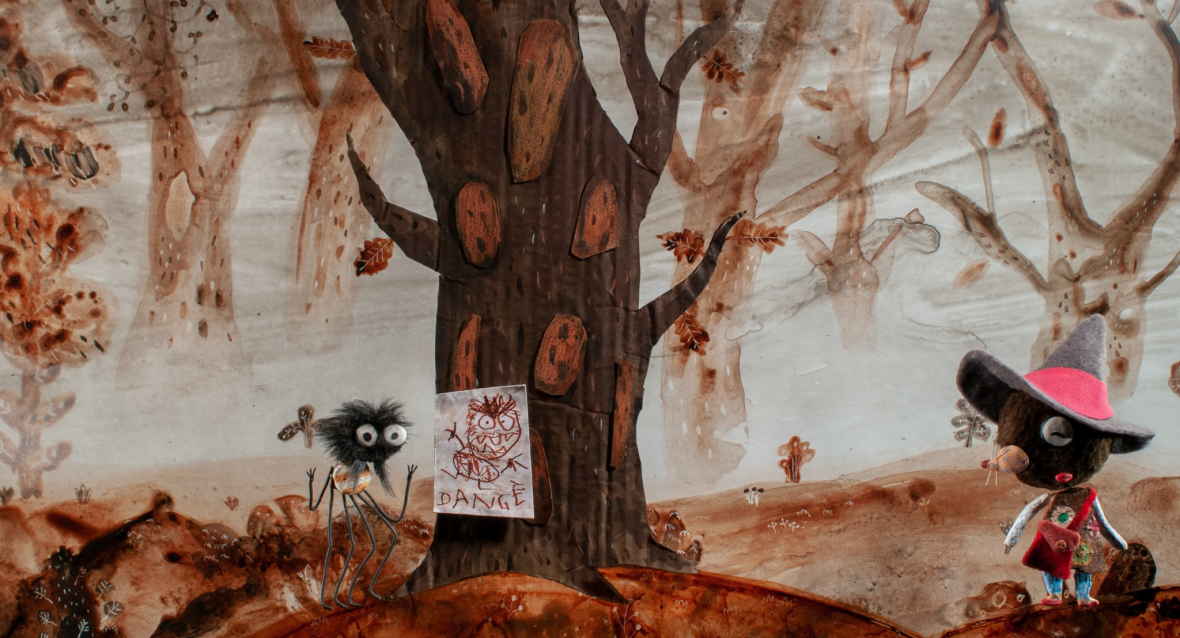 Eine kleine Spinne mit großen runden Augen zeigt dem Maulwurfmädchen ein Warnschild, das an einem Baum aufgegangen ist. Auf dem Schild ist eine Zeichnung von einem Ungeheuer mit großen Zähnen. Darunter steht das Wort "Danger", das französische Wort für "Gefahr".