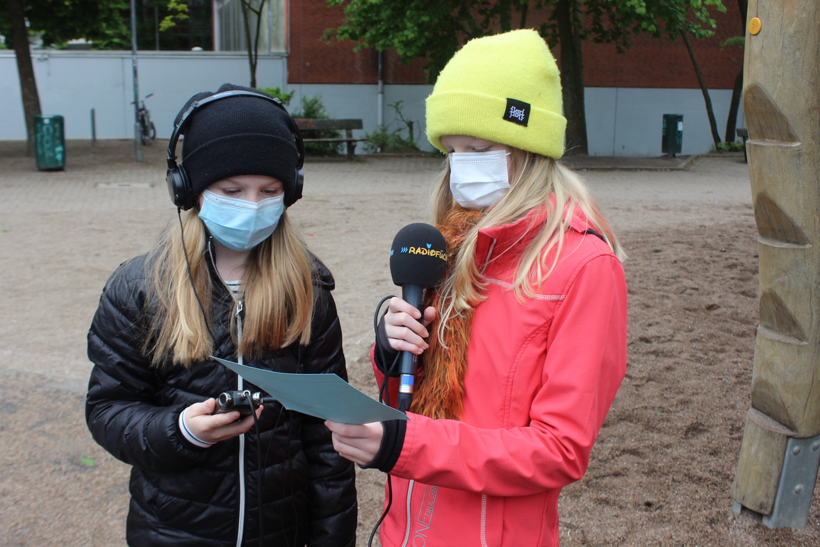Die Radiofüchse: Zwei Mädchen mit Mikrofon und Kopfhörern bereiten sich auf Interviews vor.