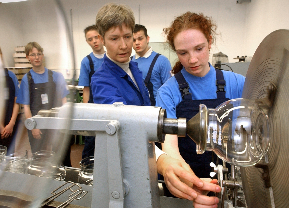 Schüler/innen bei einem Praktikum. Hier sieht man eine junge Frau an einem Schleifapparat. Die Schüler/innen lernen die Glasproduktion in Jena kennen und können selbst ein Werkstück anfertigen.