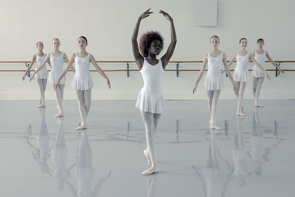 Szenenbild: Neneh im weißen Rüschenrock (im Vordergrund) ist Vortänzerin im Ballett. Die anderen Mädchen (im Hintergrund) tragen auch weiße Rüschenröcke.