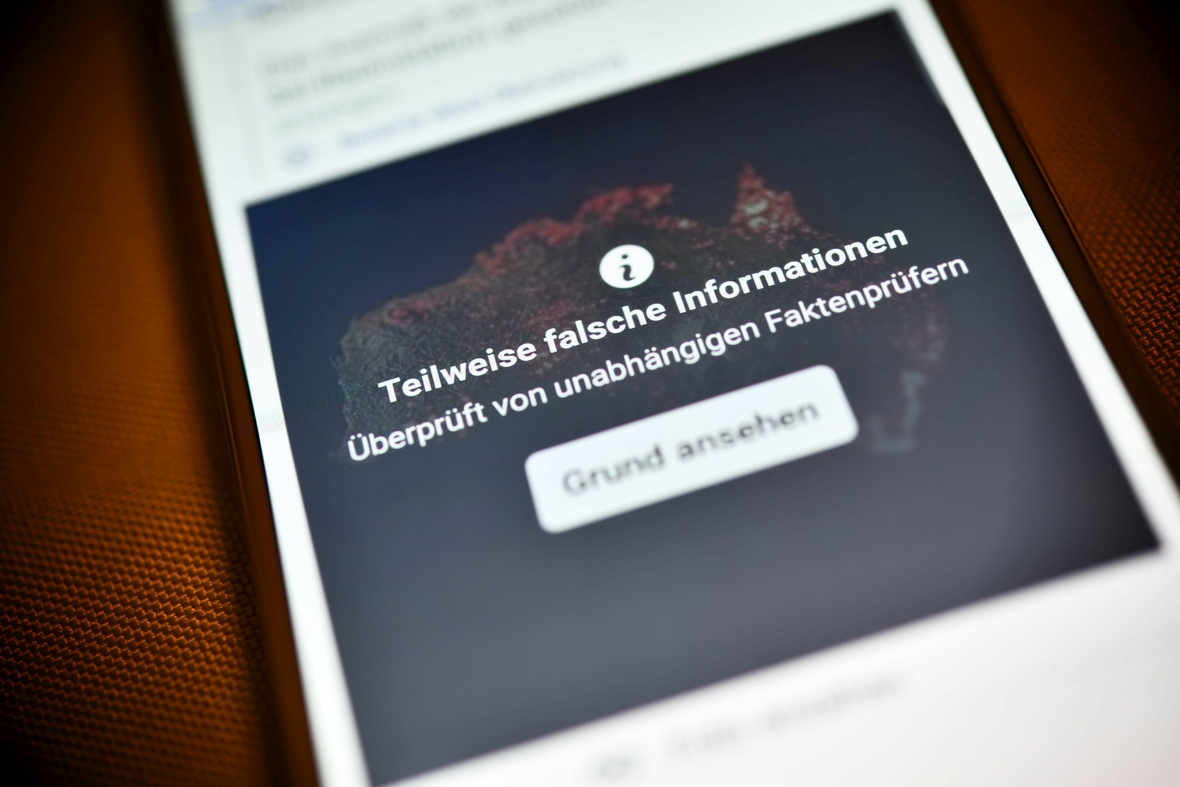 Smartphone mit aufgedeckter Falschinformation in einem sozialen Netzwerk