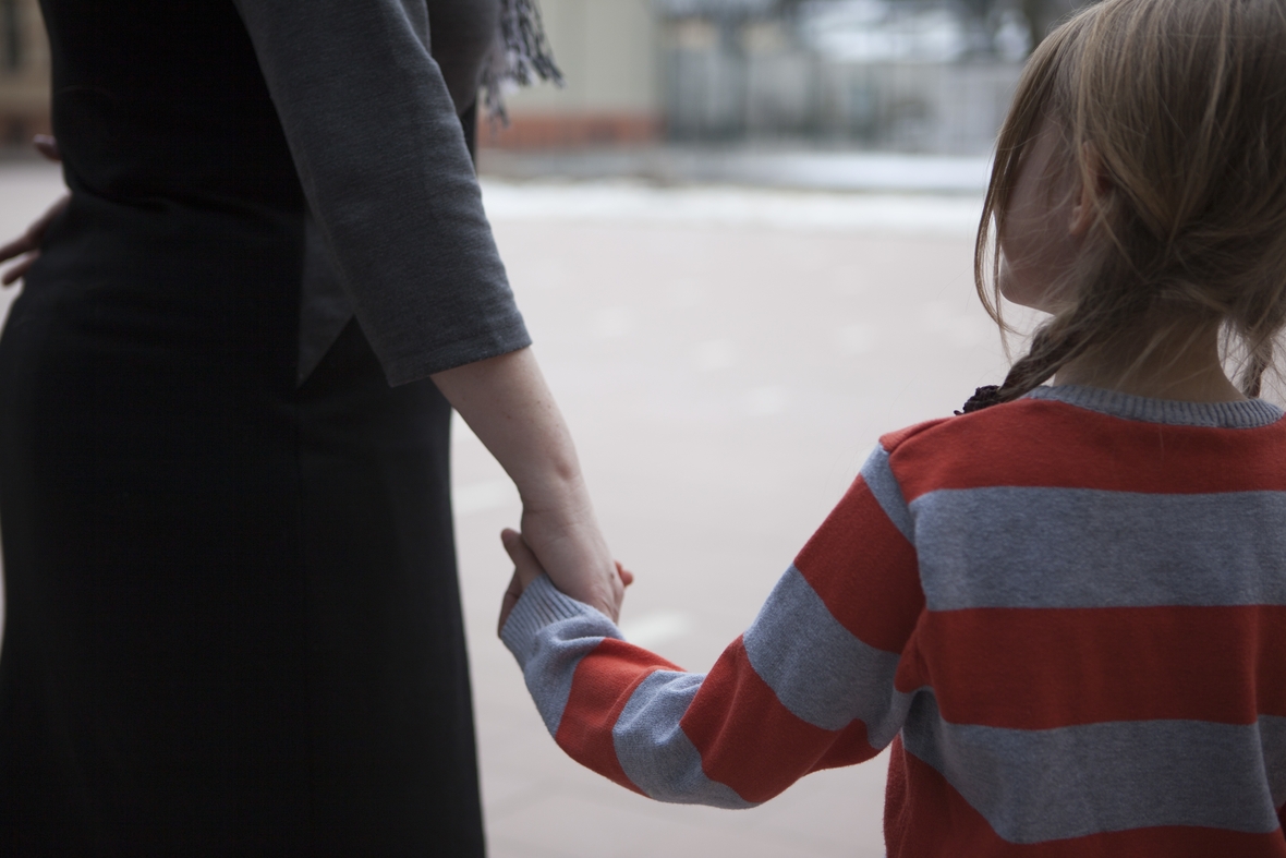 Eine Pflegemutter hält ihr Pflegekind an der Hand