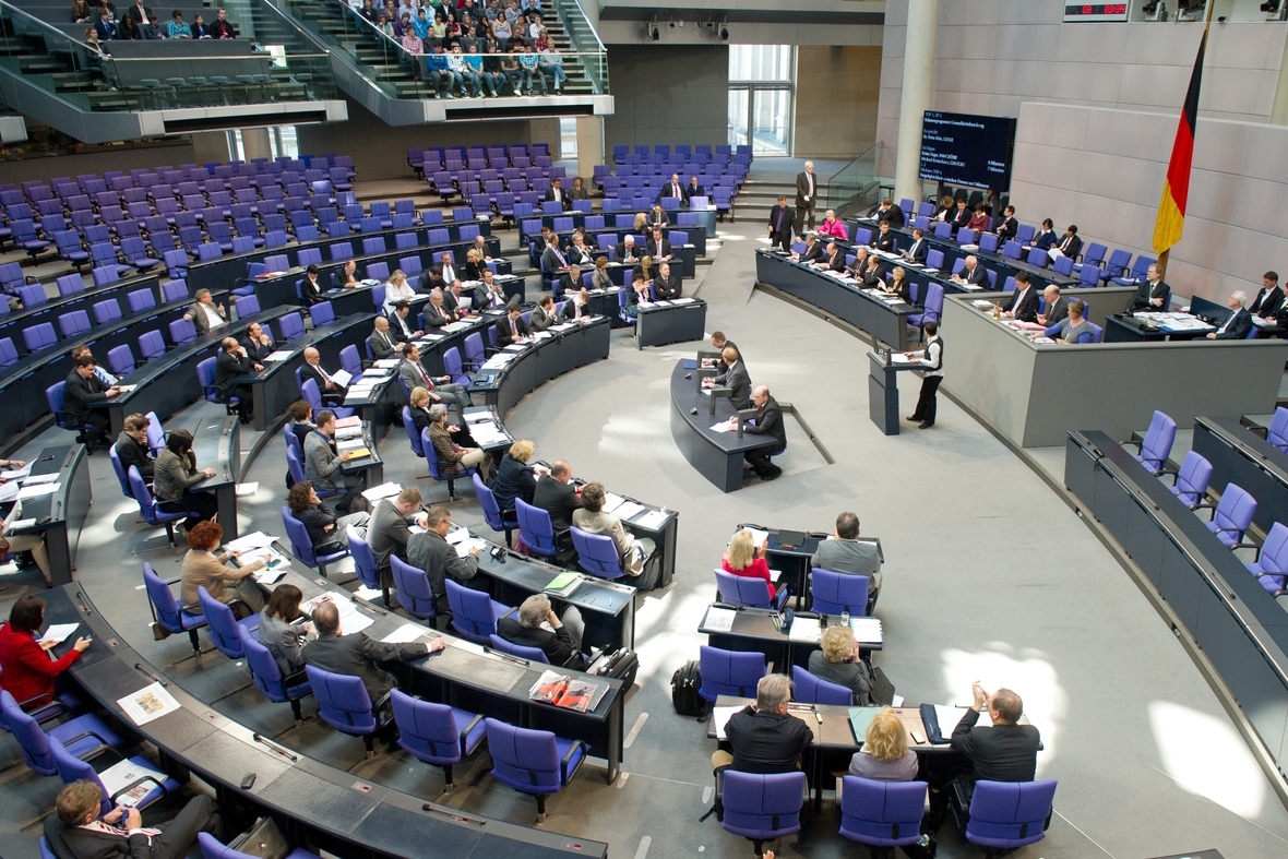 Ein Blick in den Deutschen Bundestag, wo Abgeordnete sitzen und eine Person vorträgt. 