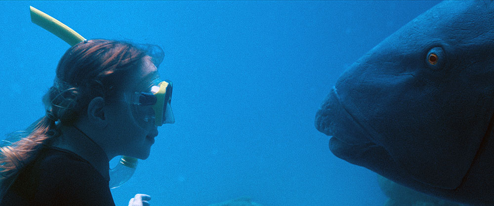 Szenenbild: Tief unten im Meer: Abby mit Schnorchel und Maske (links im Bild) und der Lippfisch Blueback (rechts im Bild) schauen sich an.