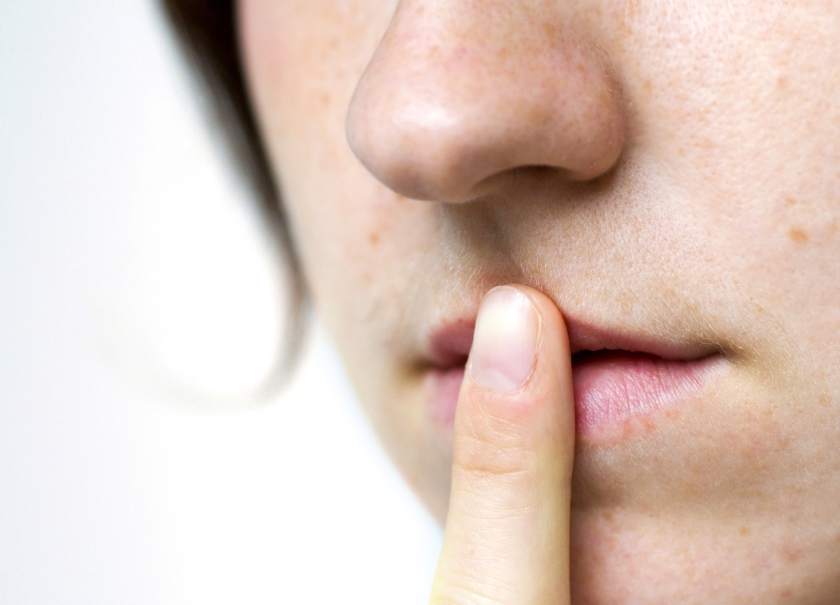 Eine Person hält ihren Finger auf die Lippen zum Zeichen für Schweigen. Verschwiegenheit ist wichtig für verdeckte Ermittler.
