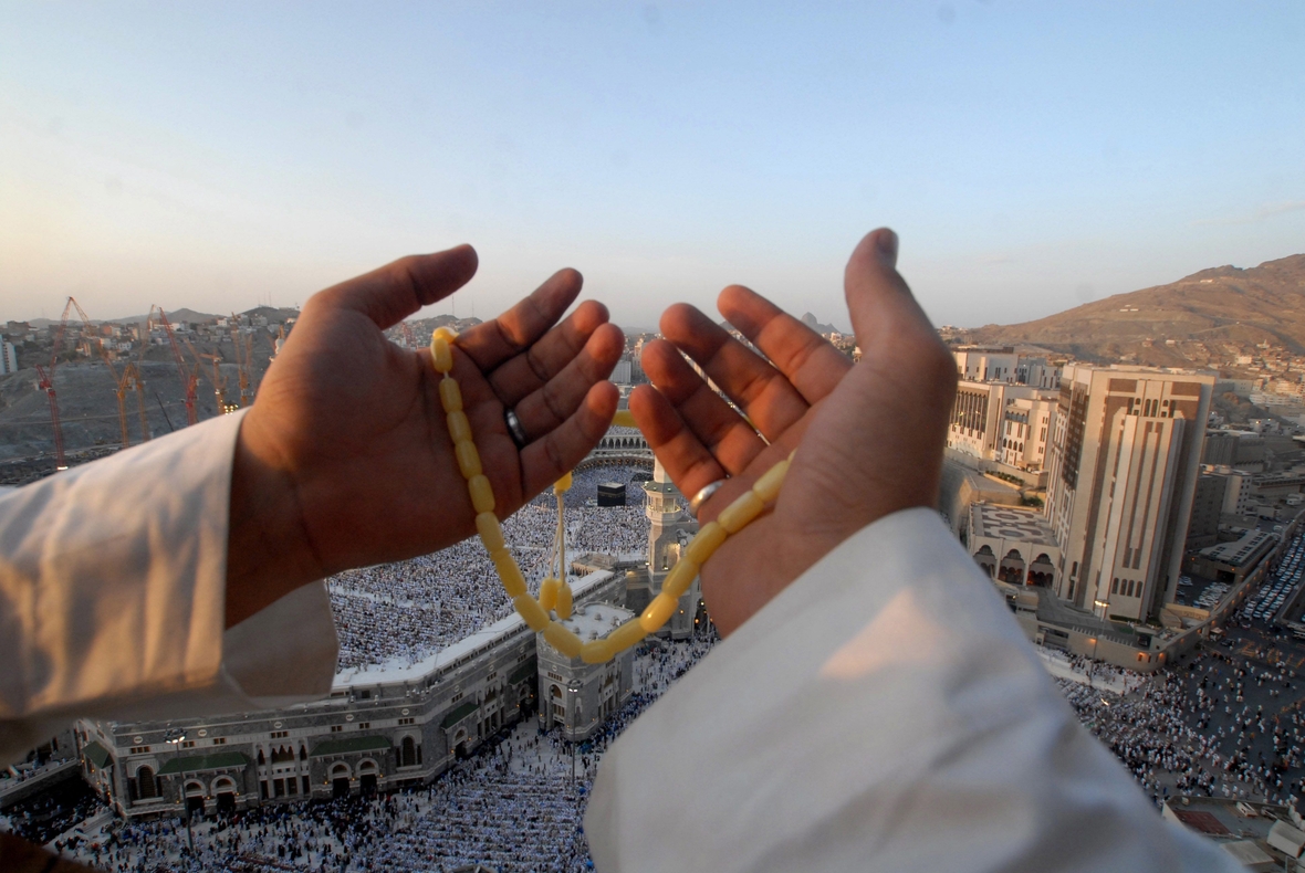 Ein Beter hält eine Gebetskette in Händen. Es ist Ramadan. Im Hintergrund stehen sehr viele Gläubige an der Großen Moschee in Mekka.