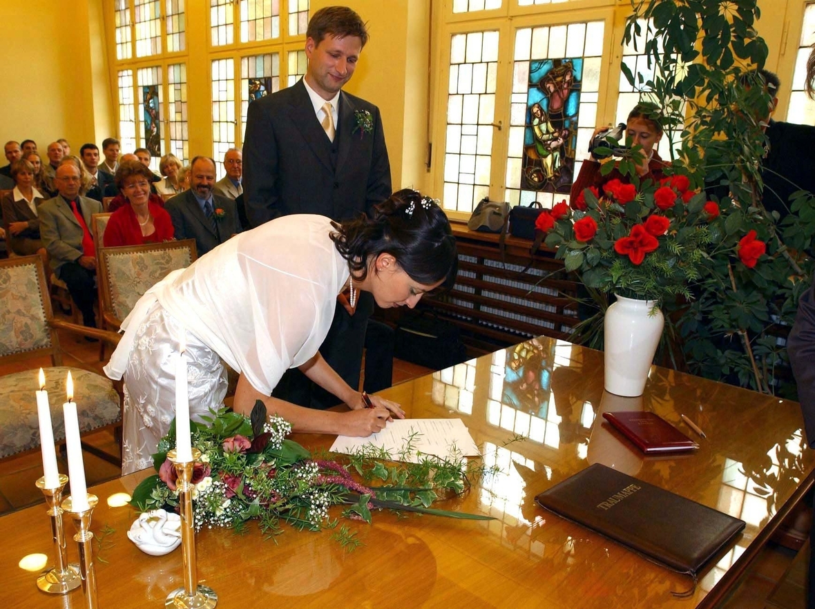 Ein Hochzeitspaar im Standesamt in Eichwalde bei Berlin. Die Ehefrau unterschreibt die Urkunde. 