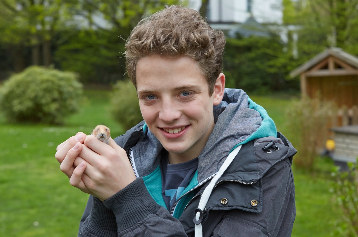 Der Schauspieler Philipp Schmitz-Elsen hält einen ausgestopften Hamster in der Hand