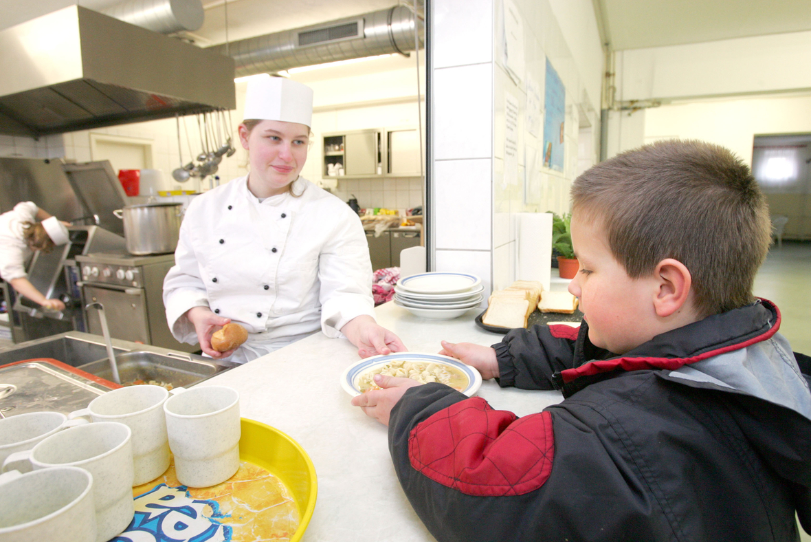 Eine warme Mahlzeit am Tag ist nicht immer selbstverständlich. Foto zeigt Kind bei der Essensausgabe in einer Mensa.