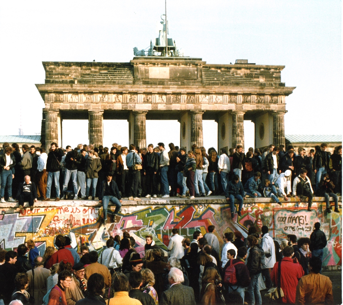 Menschen auf der Berliner Mauer nahe dem Brandenburger Tor 1989. Sie feiern den Fall der Mauer.