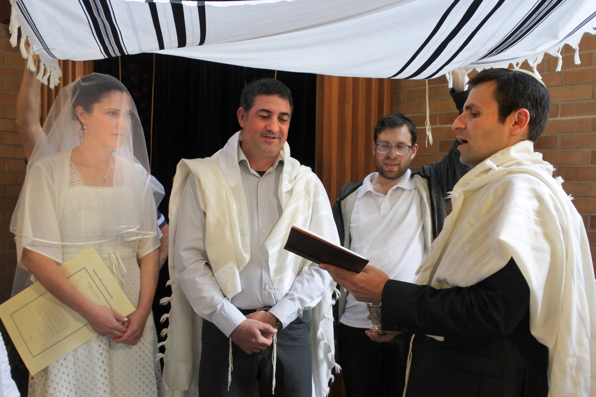 Ein Rabbi segnet bei einer Hochzeitsfeier das jüdische Brautpaar.