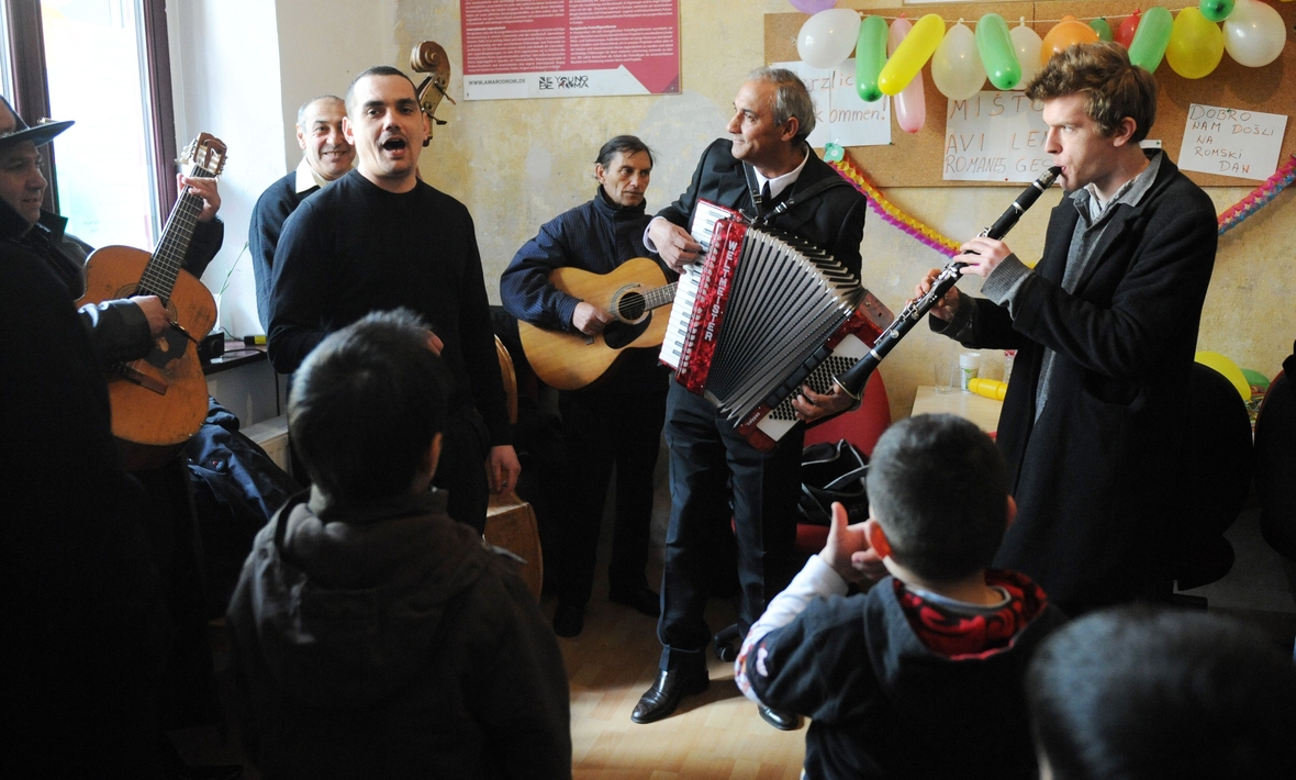 Sinti und Roma und Anwohner in Berlin-Neukölln musizieren gemeinsam. Man sieht einen Akkordeon-Spieler, zwei Gitarristen und eine Klarinette.