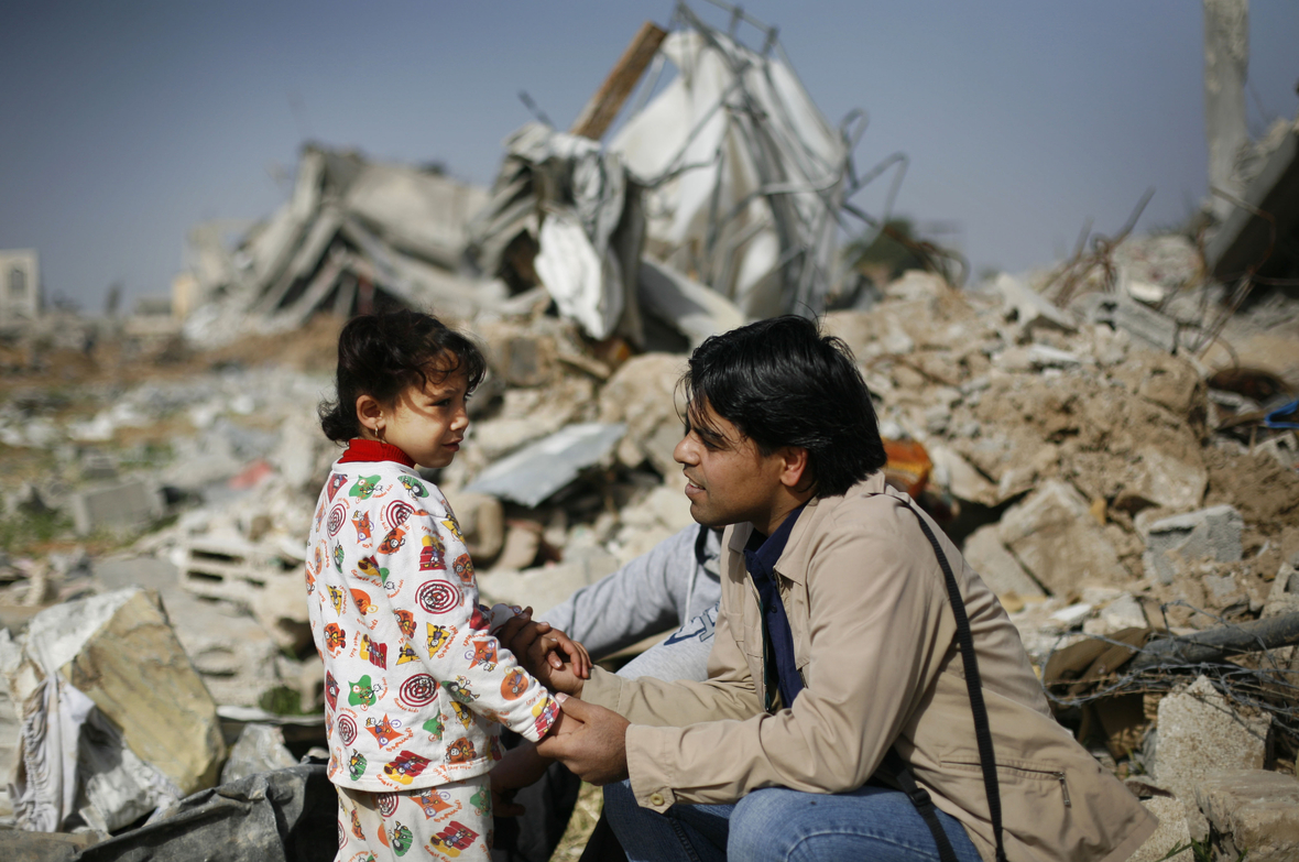 Das 5-jährige Mädchen spricht vor ihrem zerstörten Zuhause in Gaza mit einem Berater für seelische Probleme.