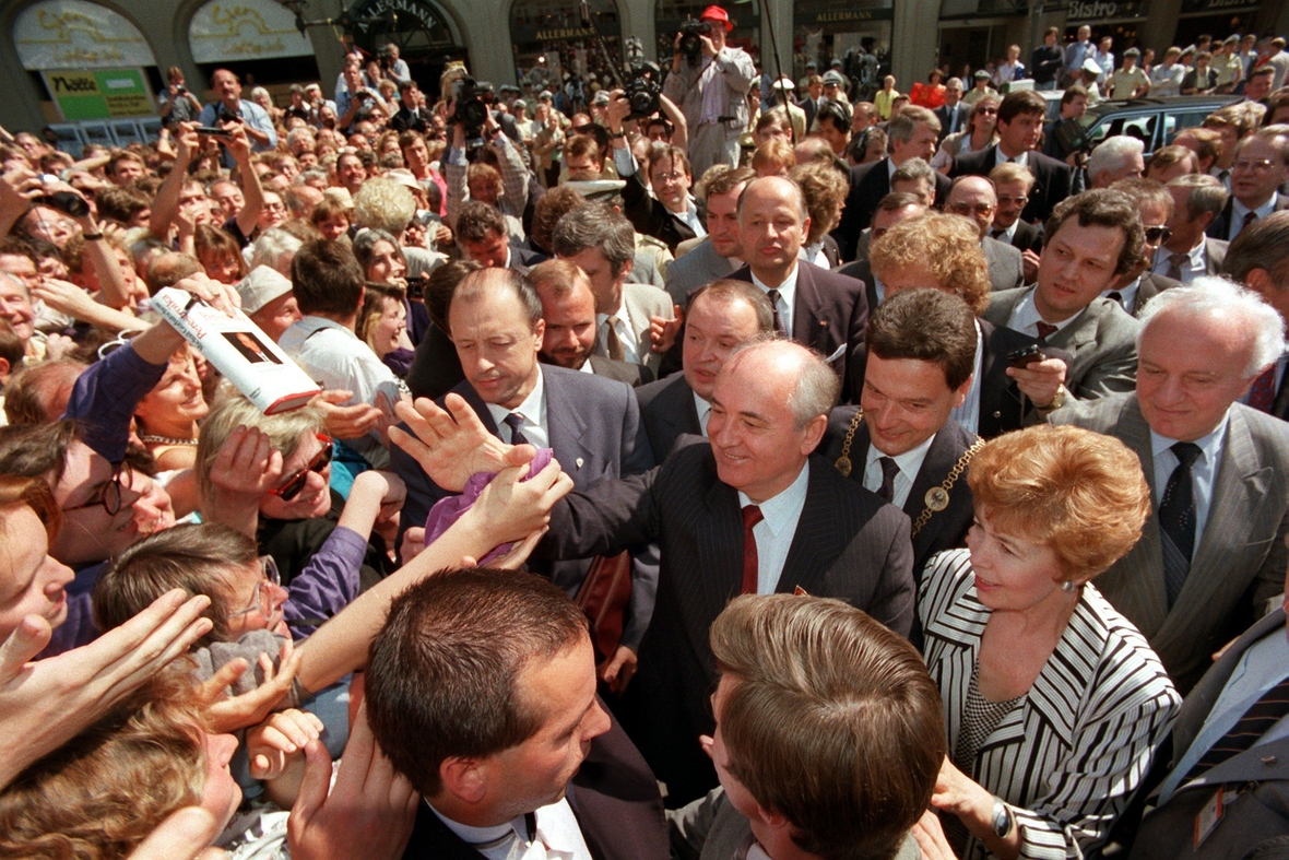 Michail Gorbatschow und seine Frau Raissa Gorbatschowa (vorne rechts) bei einem Staatsbesuch im Sommer 1989 in Bonn. Eine Menschenmenge umgibt ihn und jubelt ihm zu. 