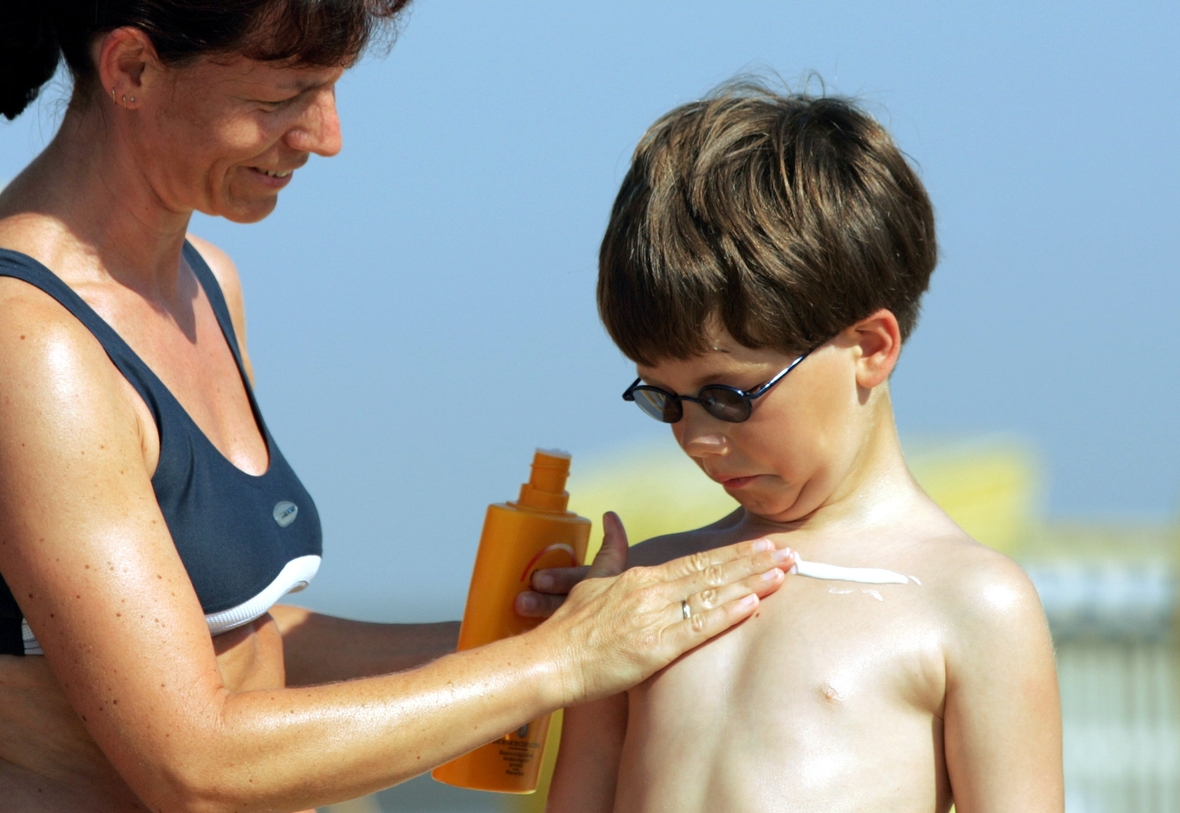 Wichtig beim Sonnenbaden: Eincremen nicht vergessen! Denn die gefährlichen UV-Strahlen können Hautkrebs auslösen. Auf dem Bild cremt eine Mutter ihren Sohn am Strand mit Sonnenmilch ein.