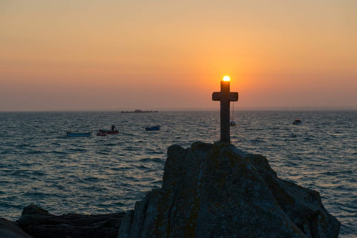Das Kreuz ist das Zeichen des Christentums. Hier ein Kreuz im Sonnenaufgang in der Bretagne (Frankreich).